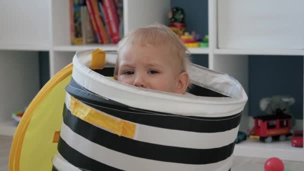 En bedrövad liten bebis Toddler gömmer sig i en lekpåse låda i barnkammaren — Stockvideo