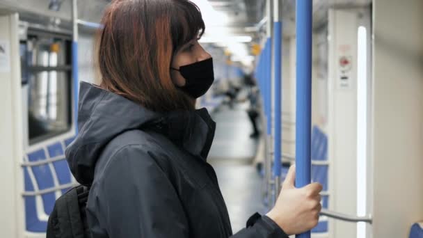 Kvinna i medicinsk mask på ansiktet rider i tunnelbanan tåg på kollektivtrafik — Stockvideo