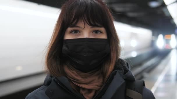 Mulher em máscara na plataforma do metrô na estação à espera de chegada do trem — Vídeo de Stock