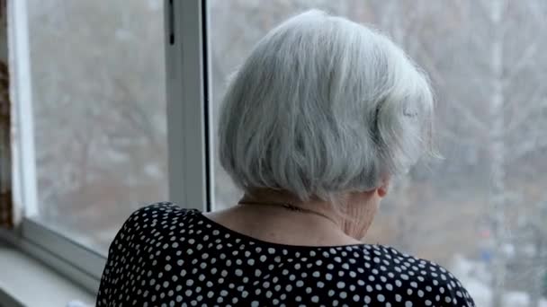 Viejo anciano caucásico mujer con gris pelo looks fuera de ventana — Vídeos de Stock