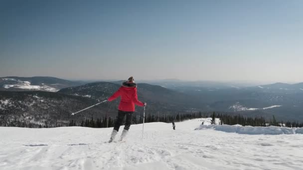 Donna sciatrice sciare sulla pista da sci in montagna il giorno soleggiato in inverno in movimento — Video Stock