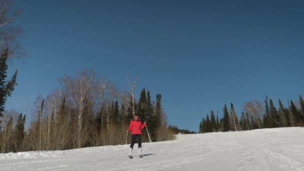 Neşeli bir kadın kayak pistinde kayak yapıyor ve gülümsüyor. — Stok video