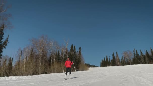 Una donna allegra scende da una pista innevata in una stazione sciistica e balla sorridendo — Video Stock