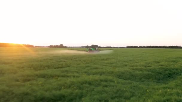 Aerial Follow Farm Tractor rocía fertilizantes en el campo agrícola al atardecer — Vídeos de Stock