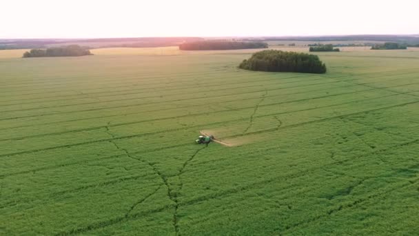 Il rimorchio aereo del trattore spruzza il fertilizzante minerale sul campo verde della fattoria al tramonto — Video Stock
