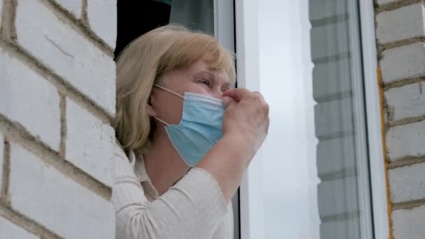 Γυναίκα κοιτάζει έξω από το παράθυρο και αφαιρεί μάσκα από το πρόσωπο λαμβάνοντας ανάσα του φρέσκου αέρα — Αρχείο Βίντεο