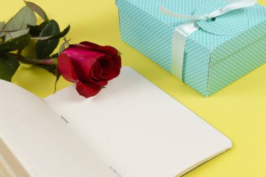 Not defterinin yanında hediye kutusu ve bir çiçek..