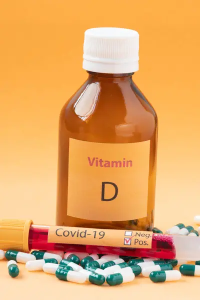Vitamin D container with capsules around it and a vacuum tube with the text Covid-19