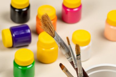 Arka planda bulanık boyalar ve gagalı tencereyle resim yapmak için sanatsal fırçalar