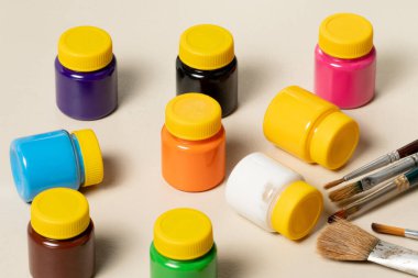 Arka planda bulanık boyalar ve gagalı tencereyle resim yapmak için sanatsal fırçalar