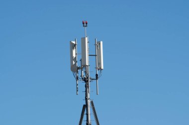 Binanın tepesinde mavi gökyüzü olan cep telefonu vericileri var.