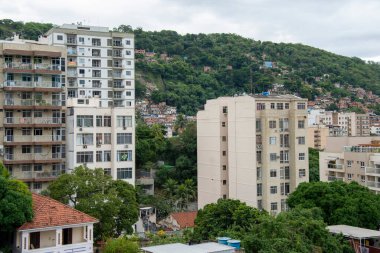 Rio de Janeiro şehrinin kentsel bir bölgesinde, arka planda Morro dos Macacos 'un gecekondu mahallelerindeki orta sınıf binalar gösteriliyor.