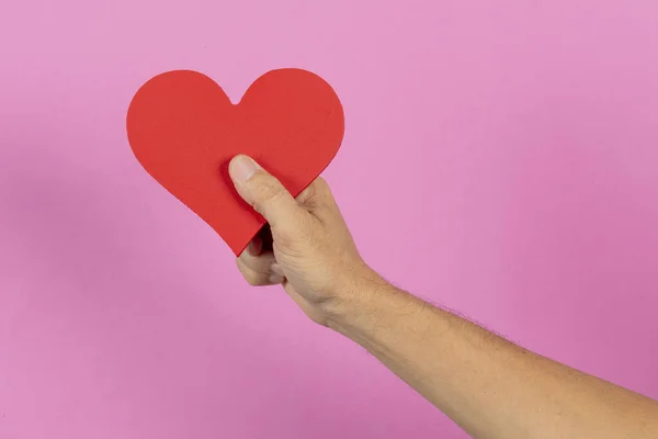 Mano Che Tiene Cuore Sul Palmo Con Uno Sfondo Rosa — Foto Stock