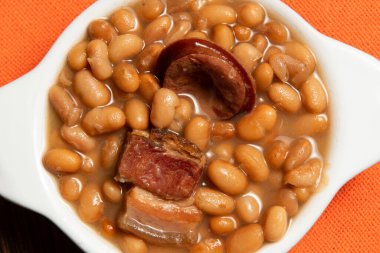 Kariyoka fasulyeli seramik tencere (feijoada) masa üzerinde hasırlı ve üst görünümde kumaşlı.