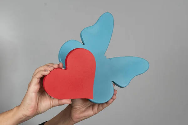 Gri arka planda kalp ve kelebek şeklinde bir kadın.
