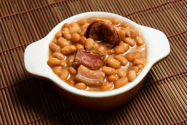 kariyoka fasulyeli seramik çömlek (feijoada) masanın üstünde, minder manzaralı.