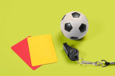 Futbol topu, sarı ve kırmızı kartlar ve hakem düdüğü.