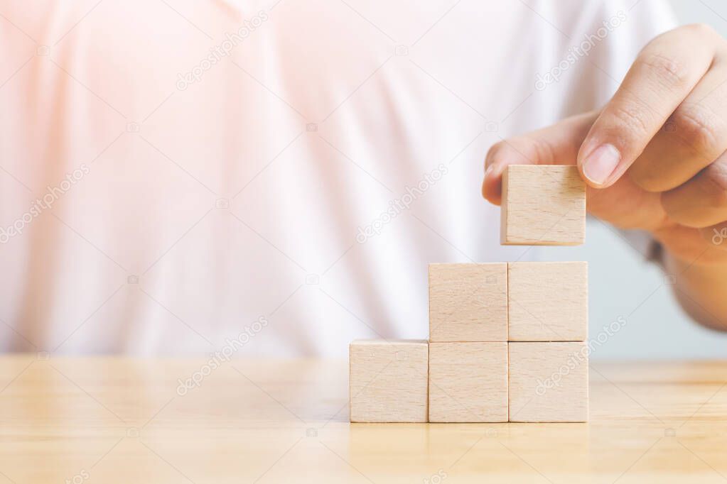 Hand arranging wood block stacking as step stair on top. Business concept for growth success process