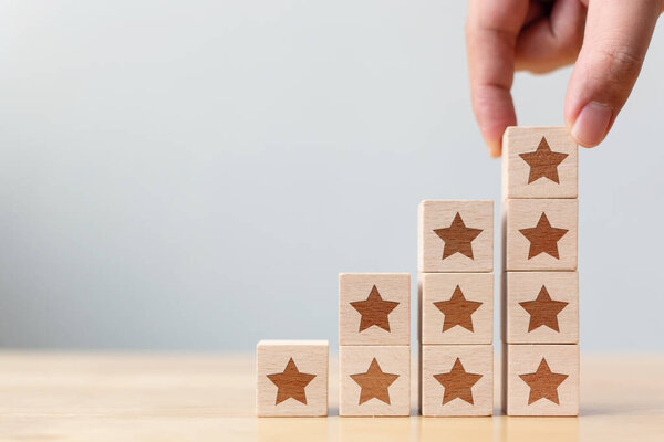 Hand arranging wood block stacking step moving up with icon five star symbol. Rating customer service satisfaction experience concept