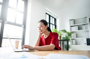 Evde çalışmak, video konferansı, çevrimiçi görüşme videosu bilgisayar ekranına bakan güzel Asyalı kadının portresi Webinar izlemek ve iş yerinde dizüstü bilgisayarda çalışmak.