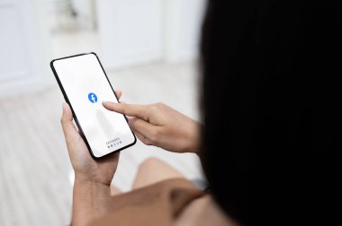 BANGKOK, THAILAND - 16 Mayıs 2020: Facebook uygulamalı cep telefonu kullanan Asyalı kadın. Sosyal medya bilgi paylaşımı ve ağ oluşturma için kullanıyor