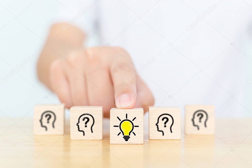 Concept creative idea and innovation. Hand choose wooden cube block with head human symbol and light bulb icon