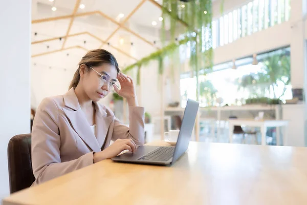 Asian business woman wear glasses and working on computer laptop in cafe