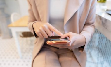 Kafede cep telefonu kullanan bir iş kadını.