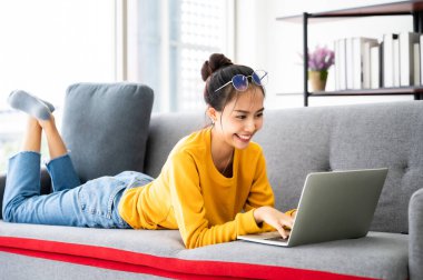 Genç Asyalı kadın evde dizüstü bilgisayar kullanıyor. Evde çalışmak, Video konferansı, Online görüşme videosu, Sanal toplantılar, Uzaktan öğrenme, E-öğrenme ve Çevrimiçi Eğitim