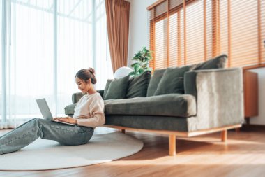 Genç Asyalı güzel bir kadın rahat koltukta dinleniyor, evinde dizüstü bilgisayar kullanıyor, sosyal ağda arkadaşlarıyla sohbet eden mutlu bir kız, haftasonunu, film izleyerek, online alışveriş yaparak geçiriyor.