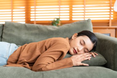 Asyalı kadın koltukta dinleniyor, işten sonra bitkin hissediyor, enerjisi yok, ya da çok çalışıyor, çok yorgun ve motivasyonsuz.