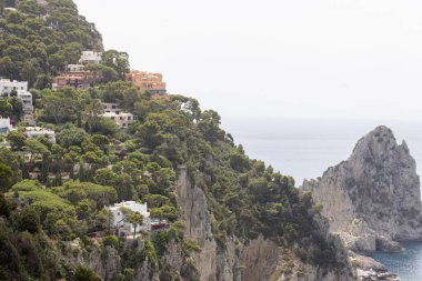 Capri Adası, İtalya - 28 Haziran 2021: Adanın kayalık kıyılarından Via Krupp ve üç küçük kayalık Faraglione di mezzo 'dan görüş