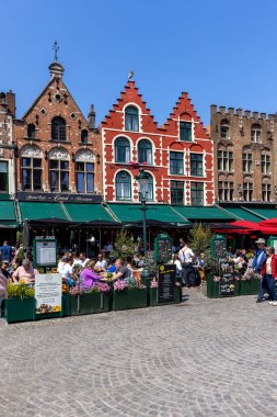 Bruges, Belçika - 19 Mayıs 2023: Market Meydanı 'ndaki geleneksel apartman evleri (Grote Markt), açık hava restoranları