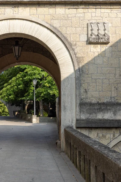 San Marino, San Marino - 10 Haziran 2025: Contrada Santa Croce caddesindeki taş kapı üzerinde üç kulesi ve sloganı olan Heraldik yardım