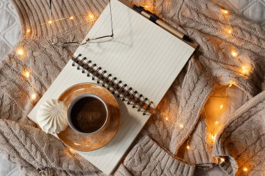 Sıcak ev atmosferi. Sıcak bej kazak, kahve bardağı, kitap. 