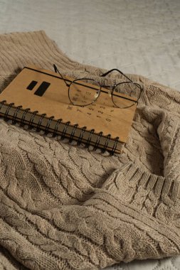 Gözlüklü ve kitaplı, bej, sıcak bir kazak. Konforlu ev b