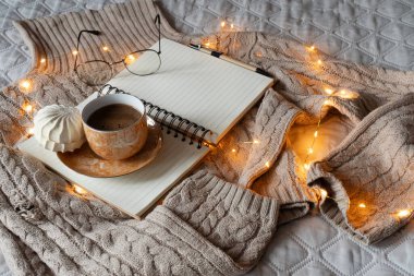 Sıcak ev atmosferi. Sıcak bej kazak, kahve bardağı, kitap. 