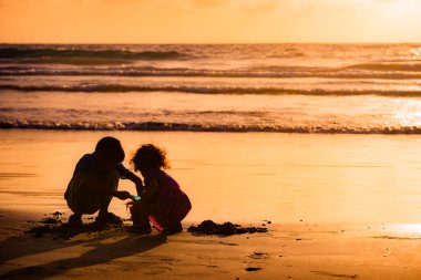 Çocuk kum deniz kenarında günbatımında Tobago içinde oyun