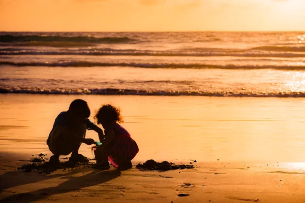 Children playing with sand by the sea at sunset in Tobago — Stock Photo, Image