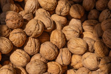 Kabuksuz cevizlerin yakın plan görüntüsü sıkıca kümelenmiş, engebeli yüzeylerini, kahverengi renklerini ve organik dokusunu vurguluyor.