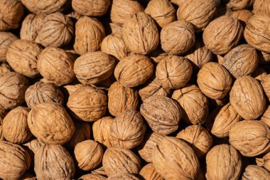 Kabuksuz, kabuksuz, kabuklu ve açık kahverengi renkli yoğun bir ceviz yığını.