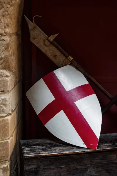 Medieval England flag shield and weapon resting on the wall side — Stock Photo, Image