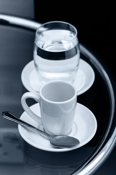 Espresso koffie lege cup en glas water op nachtkastje close-up — Stockfoto
