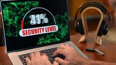  Laptop computer with security motion graphic showing 100% security with headphones and in background