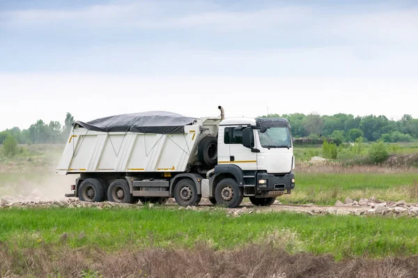 Dump truck on the gravel road carrying a load of construction materials. Truck exterior has been modified