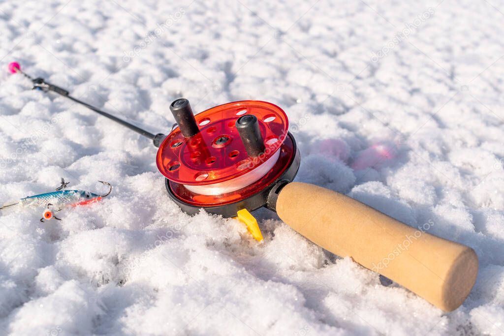 Winter fishing rod with a lure on ice closeup 4