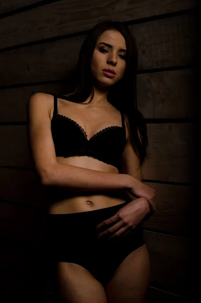 Mooi sexy meisje in een zwart badpak op een achtergrond van gepolijste platen — Stockfoto