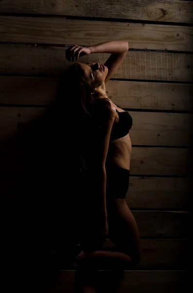 Красива сексуальна дівчина в чорному купальнику на фоні полірованих дощок — стокове фото