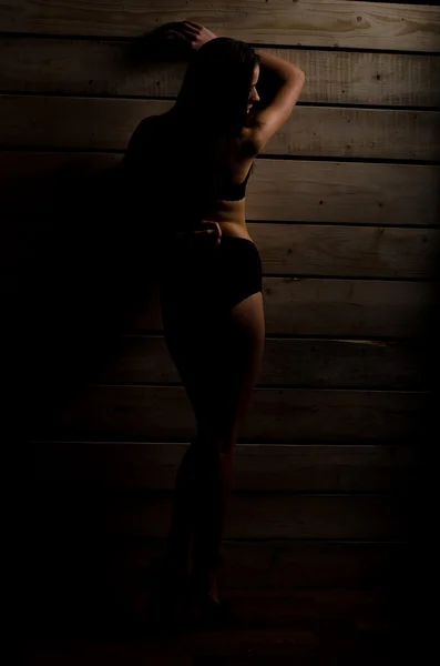 Belle fille sexy dans un maillot de bain noir sur un fond de planches polies — Photo