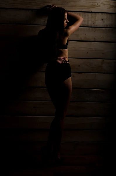 Hermosa chica sexy en un traje de baño negro en un fondo de tablas pulidas — Foto de Stock